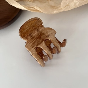 Detail view of the polished brown wood grain texture on a large French claw clip