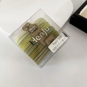 Detail view of high-elastic green hair bands in a transparent box with Japanese labels