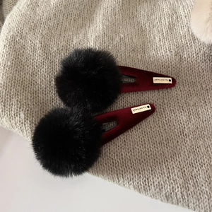 Detail of winter pom pom hair clips with golden metal tag on soft knitted background