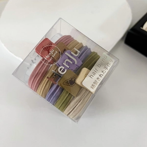 Close-up of Morandi colored seamless hair ties with matte square charms in a transparent box