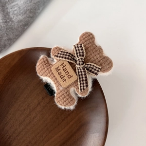 Détail de la pince à cheveux ours en tricot marron fait main sur un plateau bois