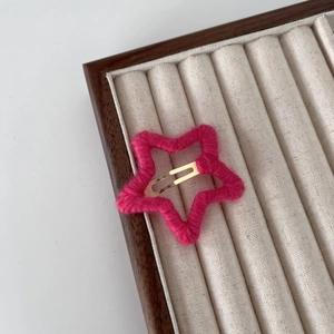 Détail de la pince à cheveux étoile rose en laine montrant la texture et le clip doré