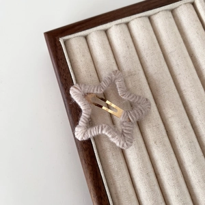 Détail d'une barrette étoile enveloppée de fil violet sur un plateau de présentation