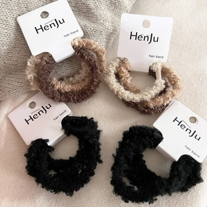 Set of 4 plush faux shearling hair scrunchies in neutral colors on display card