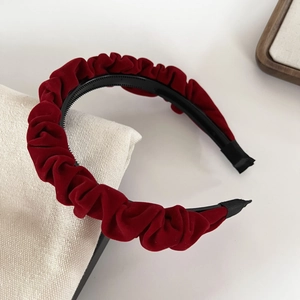 Detail of red velvet pleated headband texture with soft shadows on fabric background