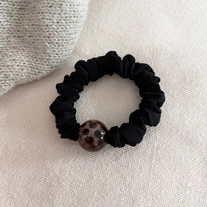 Detailed close-up of a black satin scrunchie featuring a premium leopard print bead