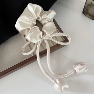 Detail of champagne satin scrunchie with elegant long ribbons and tulip charms