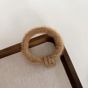 Gros plan d'un chouchou en peluche marron avec étiquette sur un plateau rustique