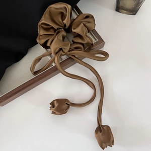 Detail of a brown satin scrunchie with long ribbons and tulip-shaped charm accents