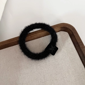 Gros plan sur un chouchou en peluche noire avec un charme carré à motif d'étoile