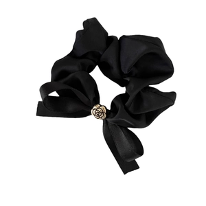 Chouchou élégant en satin noir avec nœud et rose dorée sur fond blanc impeccable