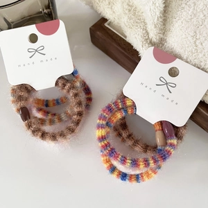 Detail of colorful plush handmade elastic hair ties on a white card with bow design