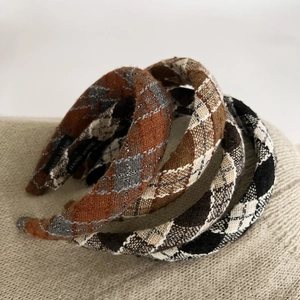 Detailed view of handmade plaid headbands with metallic thread on knit background