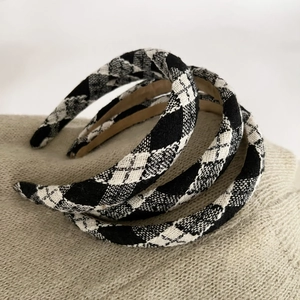 Close-up of three classic plaid headbands with silver thread on warm knitted background