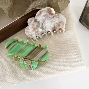 Cloud-shaped acetate hair claws with marble pattern on a minimalist wooden tray