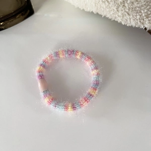 Detailed macro view of colorful plush hair tie with macaron tones and pink bead