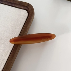 French style tortoiseshell acetate leaf hair clip in amber finish on wooden tray