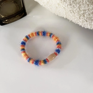 Detail of colorful plush braided hair tie with translucent resin bead on white towel