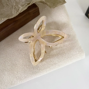 Detailaufnahme der cremefarbenen Acetat-Schmetterlings-Haarklammer mit Goldverzahnung