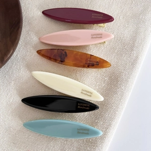 Set of 6 colorful acetate leaf hair clips with handmade gold lettering on white fabric