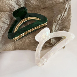 Detail view of acetate marble and pearlescent hair claws with golden metal hinges