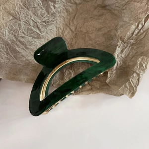 Detailed macro view of dark green acetate hair claw with internal golden metal teeth