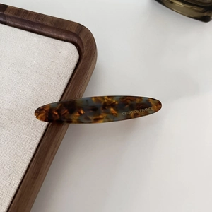 Detail of acetate hair clip with tortoise shell pattern and gold Creation France logo