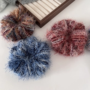 Dettaglio di grandi elastici scrunchies in maglia mista con consistenza morbida e frange