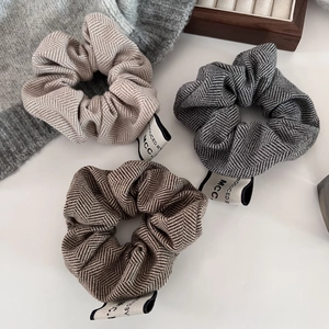 Detail of three-piece herringbone fabric scrunchies in beige, grey and brown colors