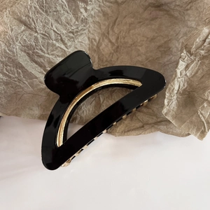 Close-up of semi-circle acetate hair claw with gold metal finish in black