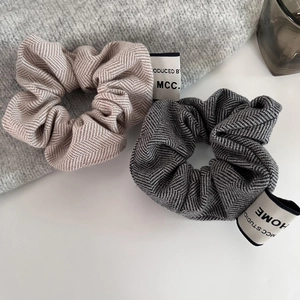 Detailed close-up of textured herringbone fabric scrunchies with woven brand labels