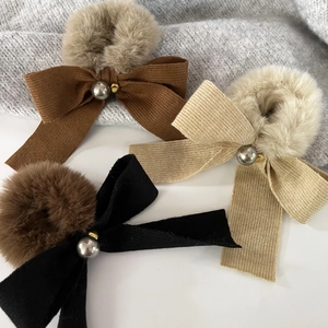 Close-up of plush bow hair ties with faux pearls in brown, beige and black variants