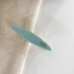Detail of mint green willow leaf hair clip with gold logo lettering on premium resin