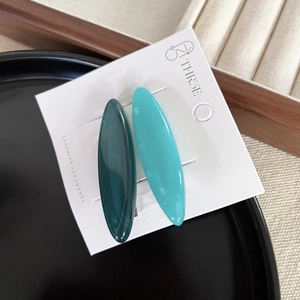 Detail of two-piece oval hair clips in marble-textured acetate with silver metal backings