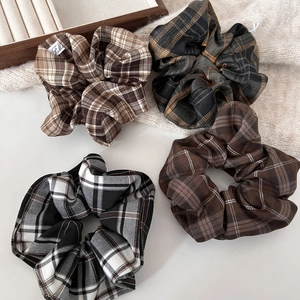 Detail showing four vintage plaid scrunchies in brown and green colors on a cozy sweater