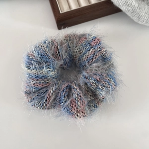 Dettaglio di un elastico per capelli in maglia soffice con filato a righe blu e rosa