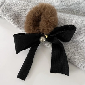 Detailed view of plush brown fur ball and black grosgrain ribbon bow with a silver bead