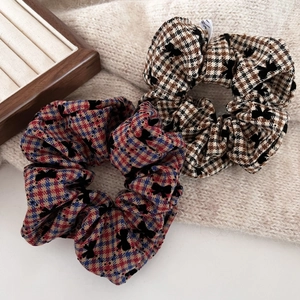 Detail of red-blue plaid and houndstooth scrunchies with black flocked bows on knit fabric