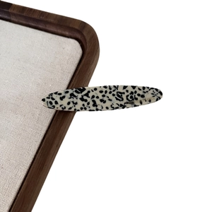Dalmatian spotted acetate hair clip with Creation France logo on a linen display board