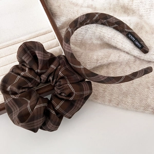 Brown plaid hair scrunchie and thin headband set displayed on beige knitwear background