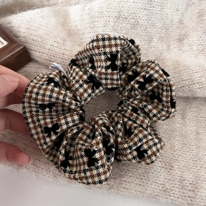 Detailed view of houndstooth scrunchie with flocking bowknot and autumn fabric texture