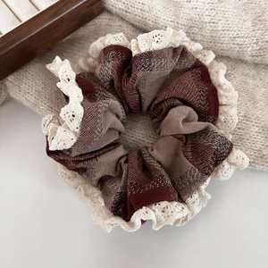 Detail of hazelnut brown plaid scrunchie with lace trim on a soft knit fabric