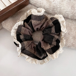 Close-up of hazelnut plaid scrunchie with delicate lace edges on a wooden box