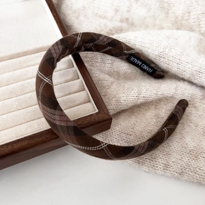 Macro detail of retro brown plaid padded headband featuring a handmade inner label