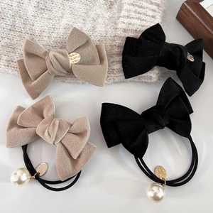 Detailansicht von Samtbogen-Haarspangen und Perlen-Haargummis in Schwarz und Beige
