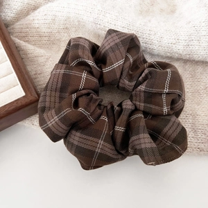 Close-up of retro brown plaid scrunchie on soft knit fabric for autumn hair styling