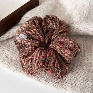 Close-up of knit plaid hair scrunchie with soft texture and brand label in warm autumn tones