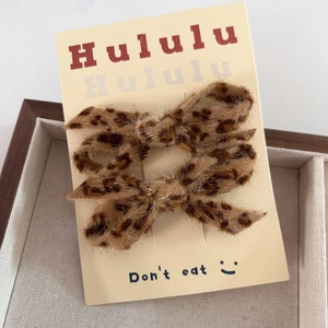 Elegant leopard print bow hair clips set on display card in a wooden jewelry box