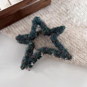 Dettaglio di un fermaglio a stella in maglia verde scuro con puntini colorati