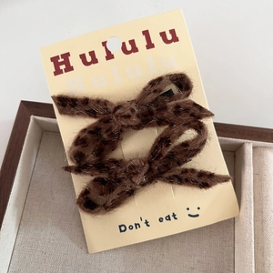 Detailed view of two leopard print plush bow hair clips displayed on a branded card